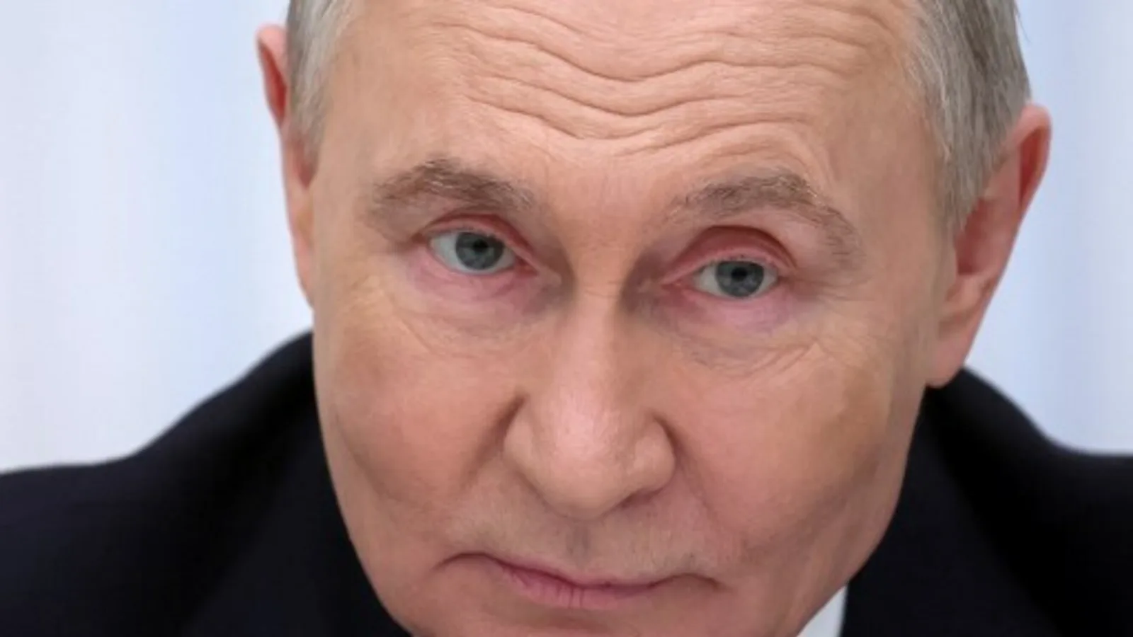 Vladimir Putin în timpul unei conferințe, cu un expresie serioasă.