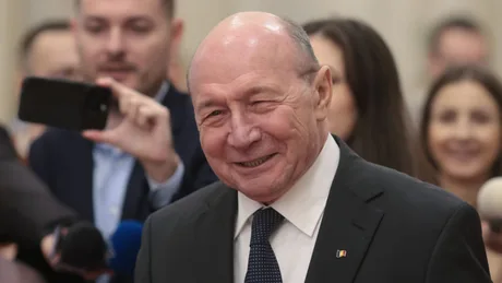Traian Băsescu zâmbind în fața presei, într-un cadru oficial.