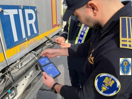 Un agent vamal verifică documentele unui camion în trafic.