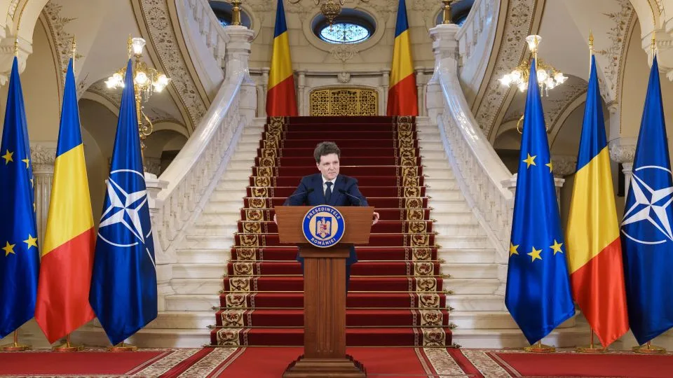 Nicușor Dan susține o conferință de presă în fața drapelului României.