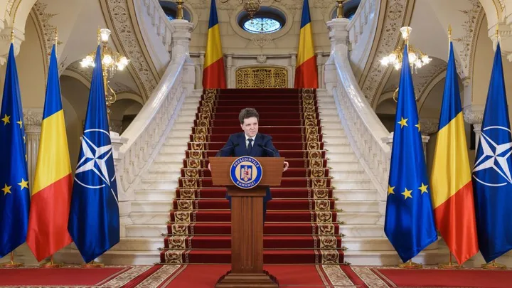 Nicușor Dan susține o conferință de presă în fața drapelului României.