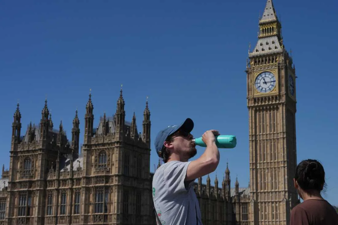 Persoane pe stradă în fața clădirii Parlamentului din Londra, într-o zi călduroasă.