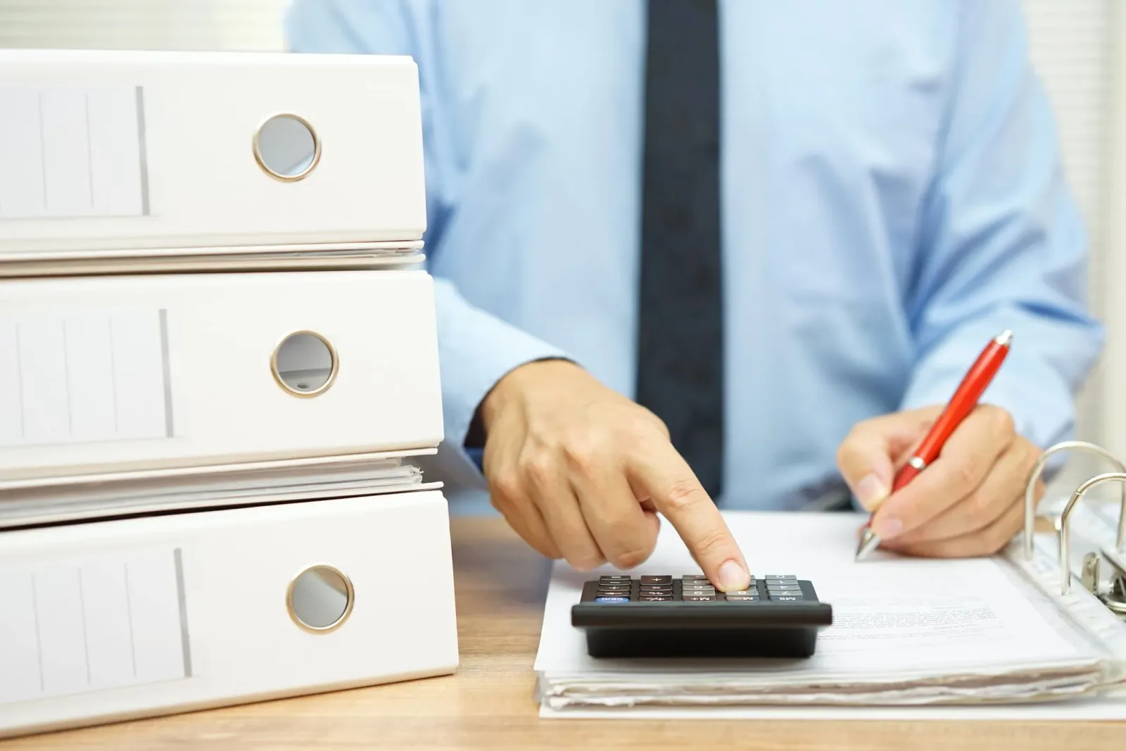 Persoană care completează documente financiare și folosește un calculator.