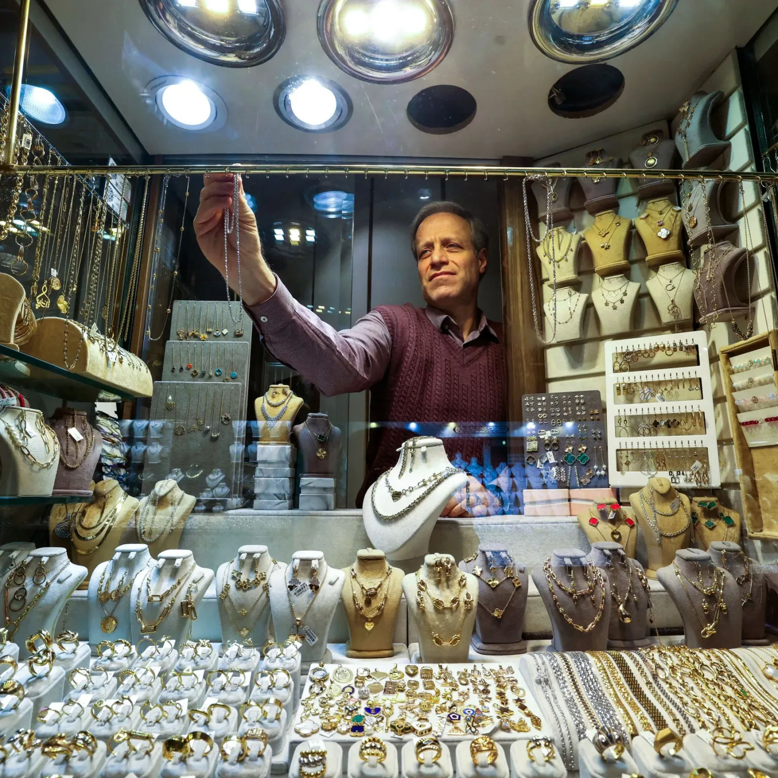 Un bijutier aranjează bijuterii din aur într-un magazin elegant.