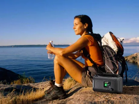 Femeie relaxându-se lângă apă, cu un radio portabil alături.