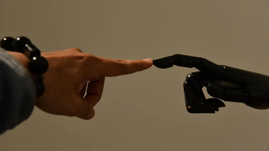 O mână umană atinge un deget robotic într-un context tehnologic avansat.