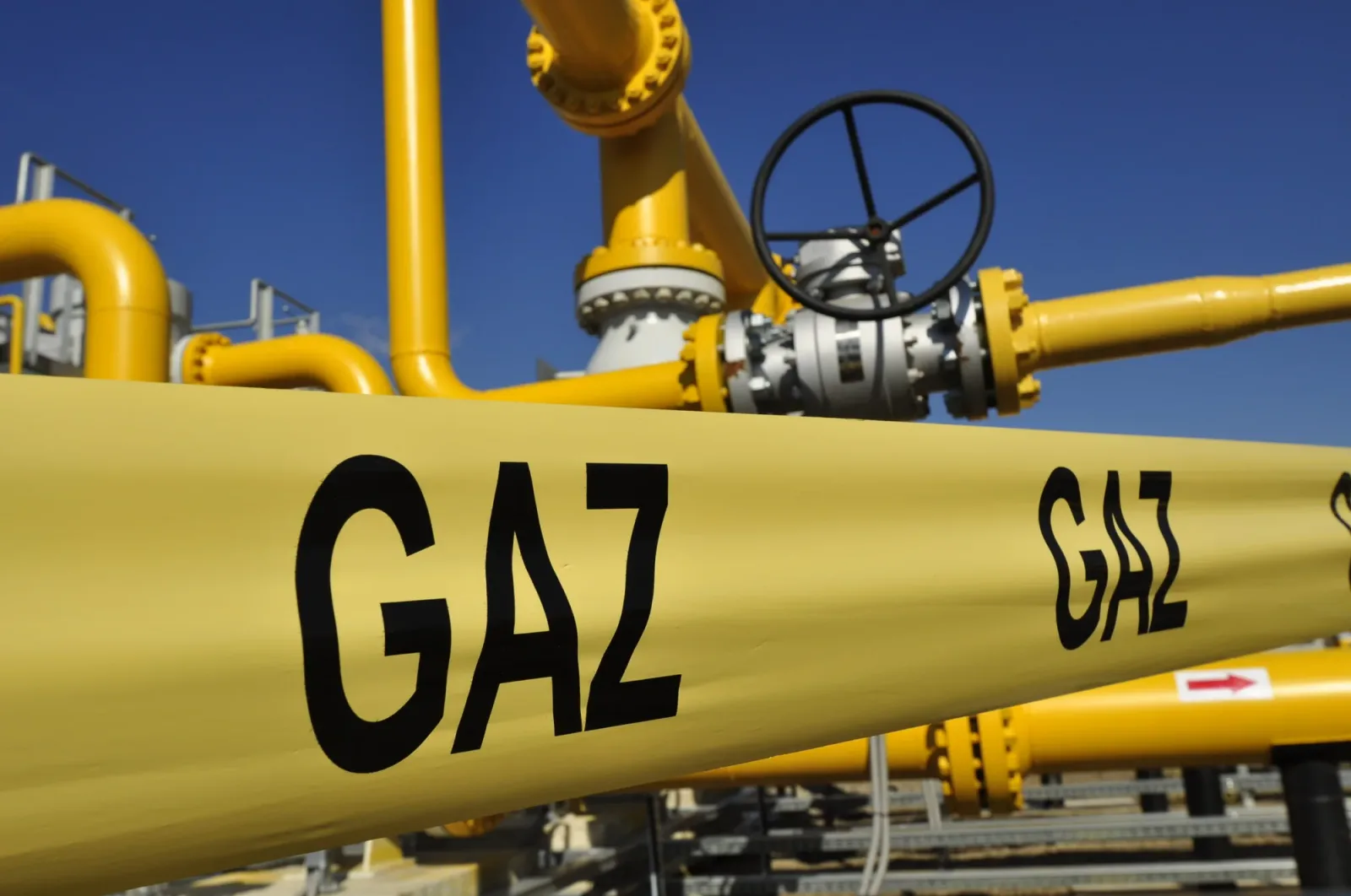 Conducte de gaz cu semne de avertizare pe fundal albastru.