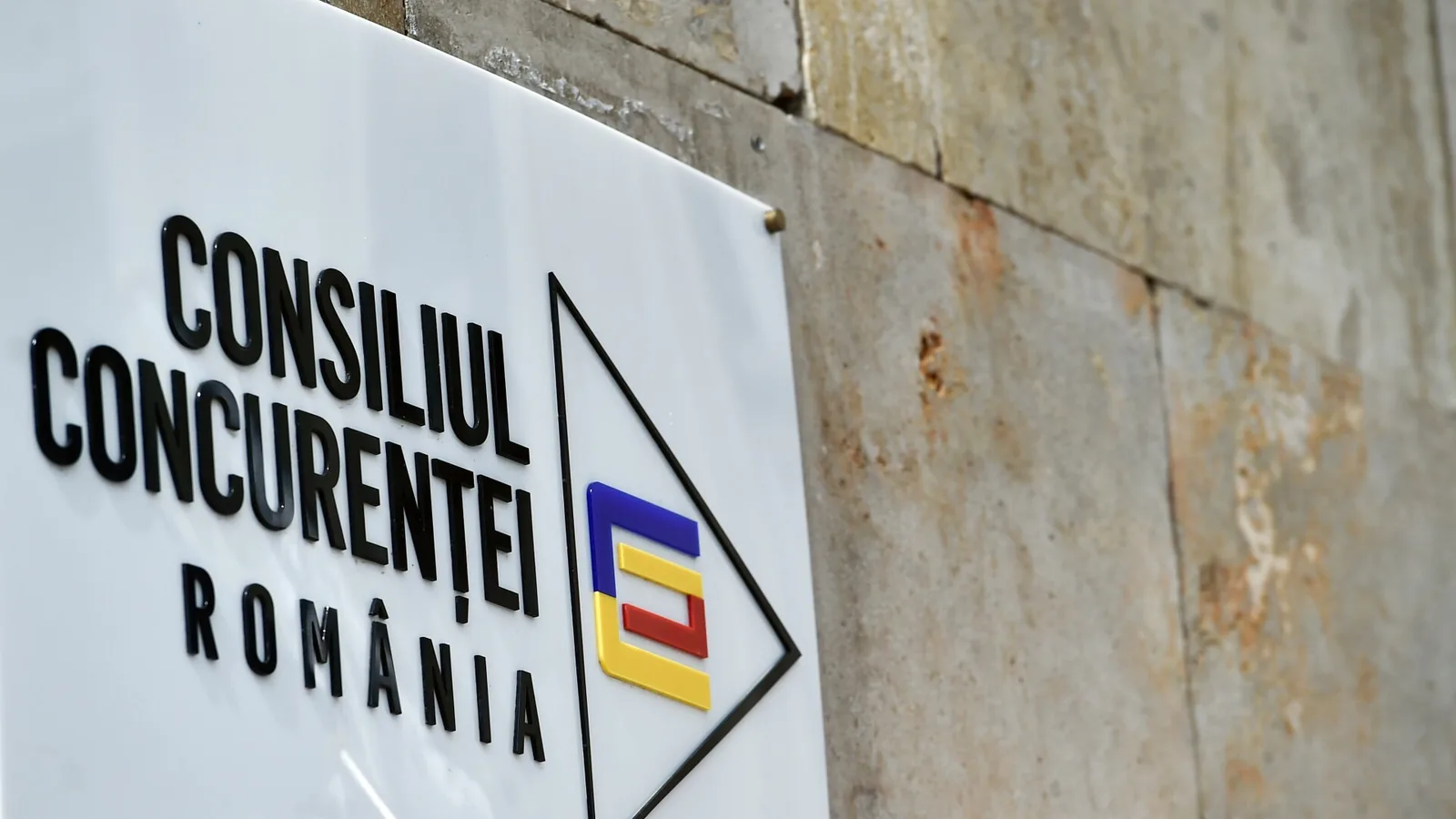 Logo-ul Consiliului Concurenței pe un fundal texturat.