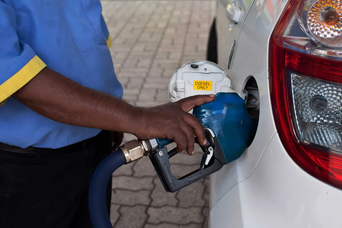 Un angajat al unei stații de benzină umple un rezervor cu motorină.