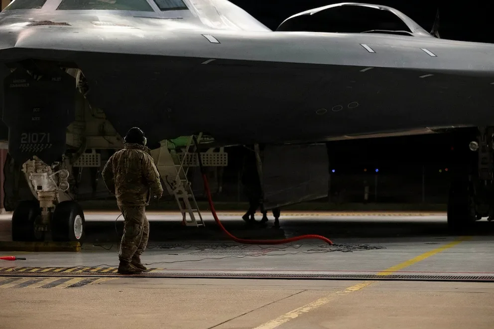 Un tehnician inspectează un bombardier B-2 Spirit înainte de zbor, în condiții de noapte.