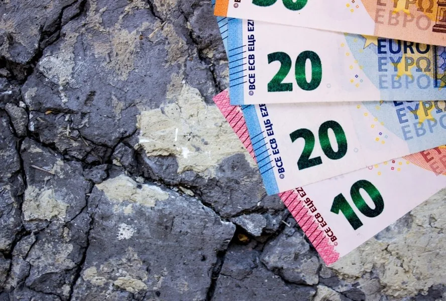 Bancnote euro pe un fundal crăpat, simbolizând tranziția economică.