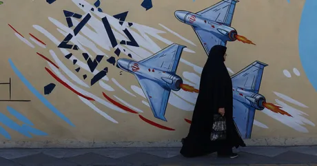 O femeie trece pe lângă un mural cu avioane de luptă în Teheran.