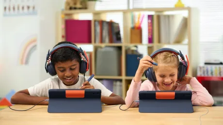 Doi copii folosesc iPad-uri cu huse Logitech, concentrându-se pe activități educaționale.