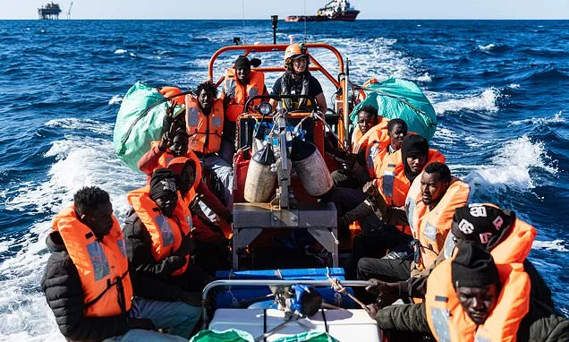 Migranți pe o barcă în largul mării, purtând veste de salvare.