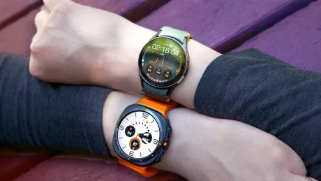 Două ceasuri inteligente Samsung purtate pe încheieturi, cu design modern și culori diferite.