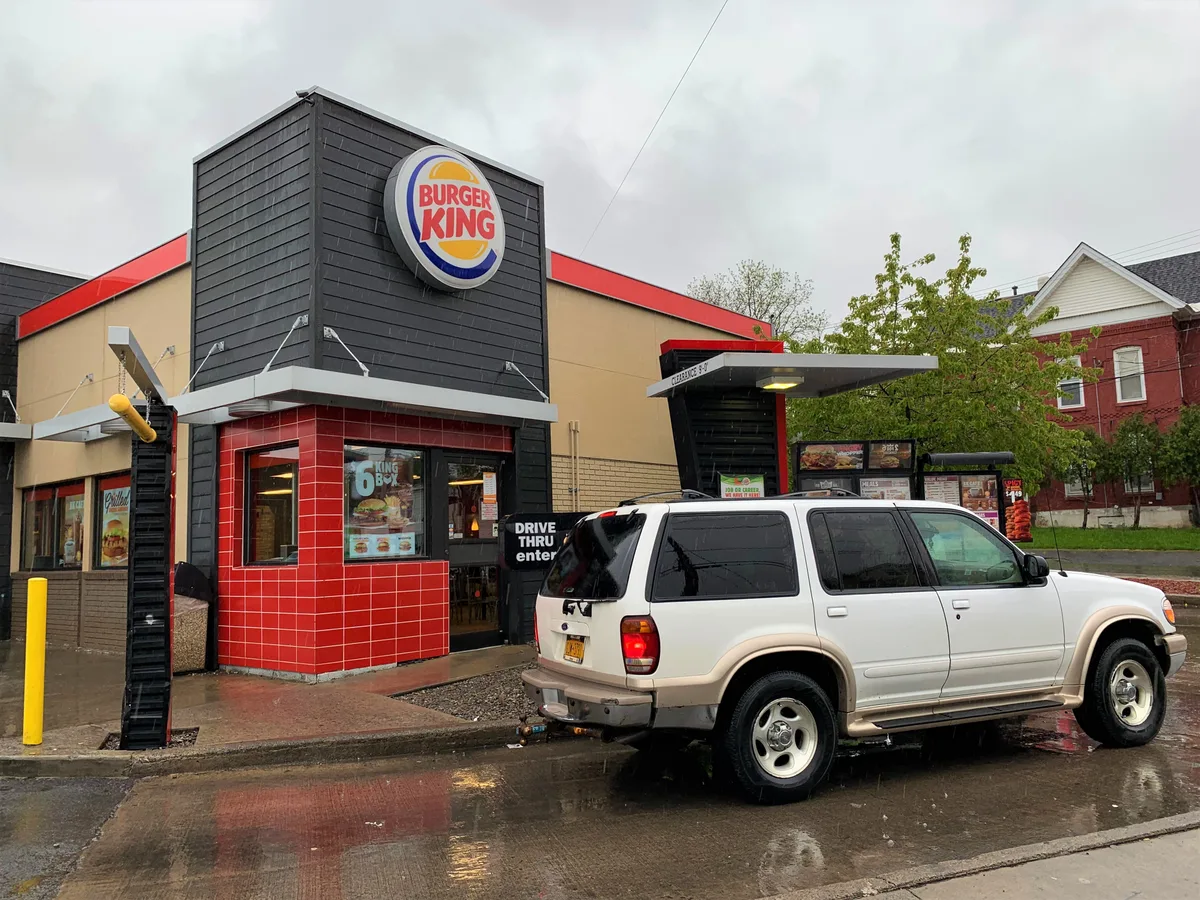 Restaurant Burger King cu zona drive-thru și un SUV parcat.