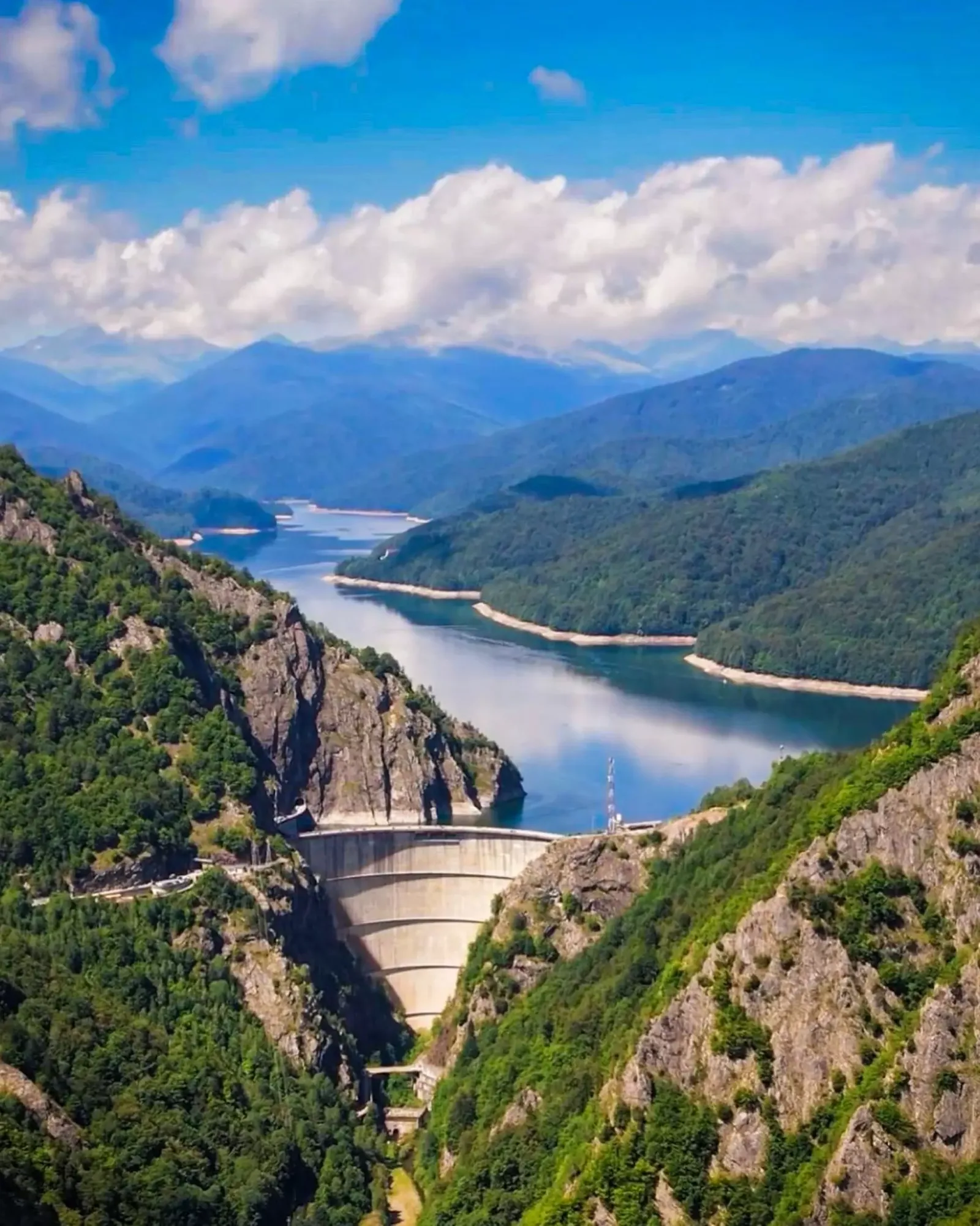 Peisaj montan cu lacul Vidraru și barajul în prim-plan.