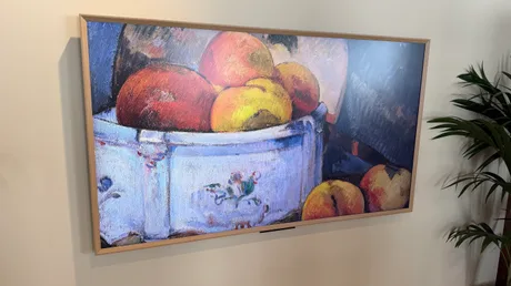 Televizor cu un peisaj artistic, expus pe un perete alb.