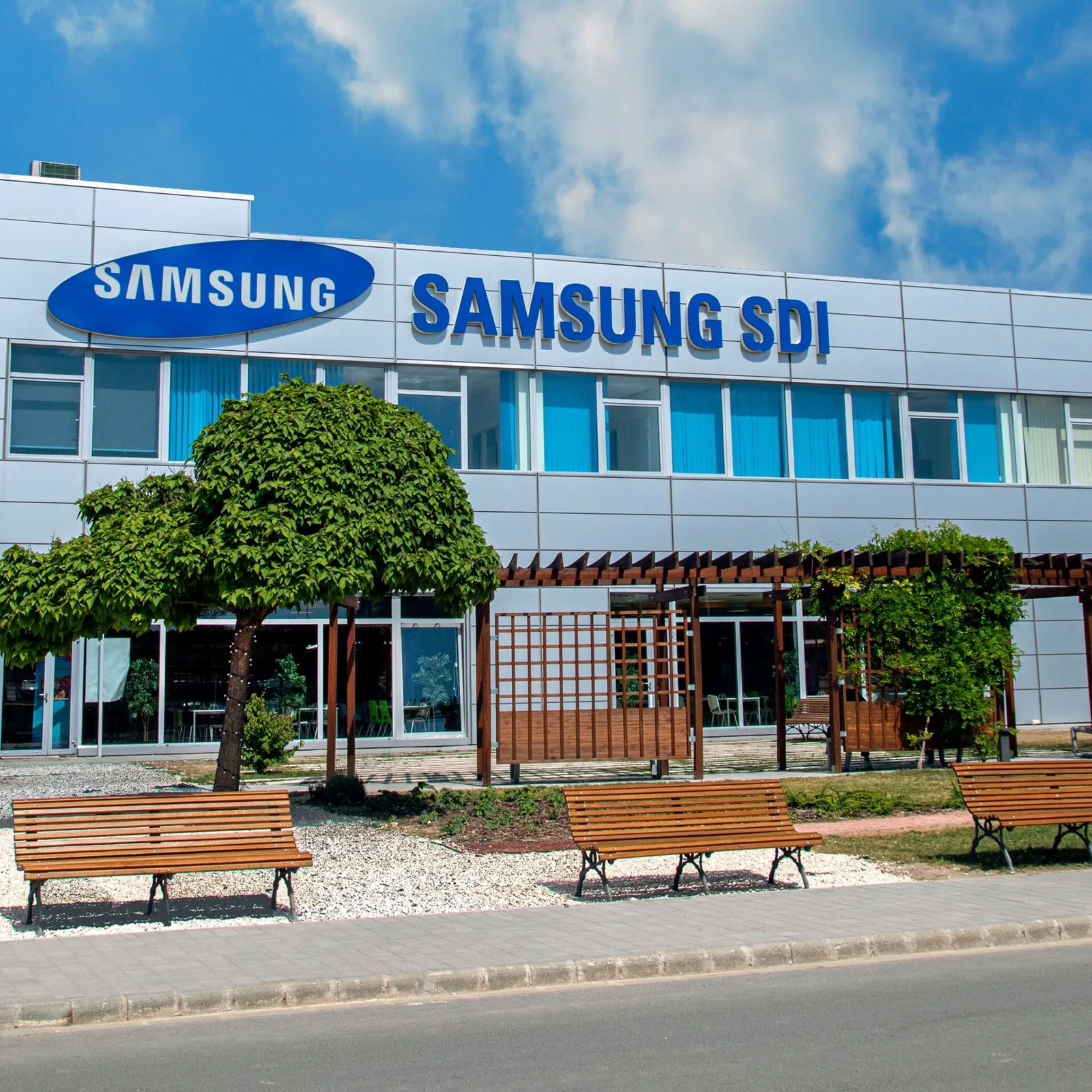 Fabrica Samsung SDI din Göd, Ungaria, cu vegetație și bănci în față.