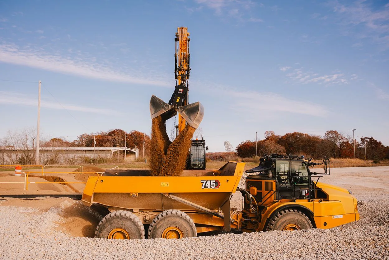 Utilaj de construcții Cat în acțiune, mutând material pe un șantier.