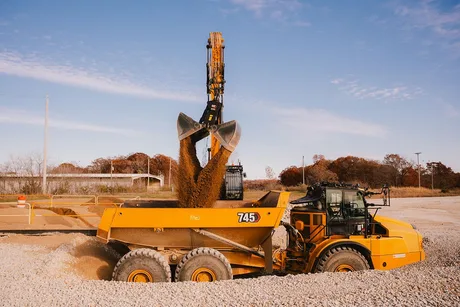 Utilaj de construcții Cat în acțiune, mutând material pe un șantier.