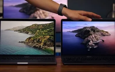 Două laptopuri MacBook cu ecrane diferite, pe un birou.