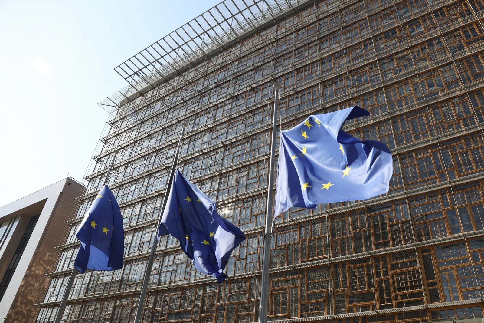Clădirea Consiliului Uniunii Europene cu steagurile UE fluturând în față.
