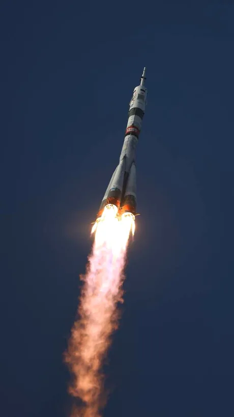 Racheta de lansare înălțându-se spre cer, simbol al explorării spațiale.