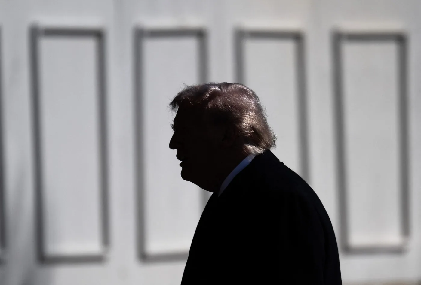 Silhouette a unei persoane în fața unui zid alb.