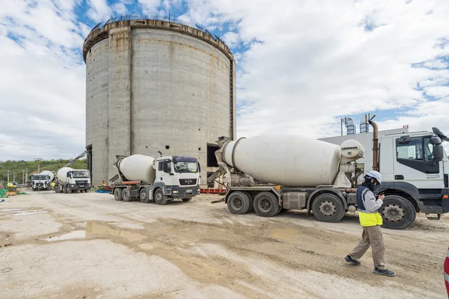 Lucrări de construcție la Unității 1 Cernavodă, cu camioane și utilaje pe șantier.