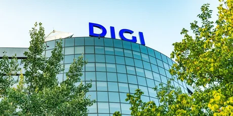 Clădire Digi cu logo pe fond de cer albastru și copaci verzi.
