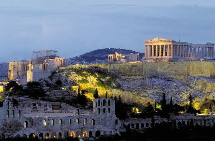 Peisaj urban din Grecia, cu monumente istorice iluminate noaptea.