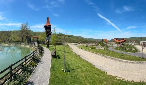 Peisajul Parcului Poeților din Porumbenii Mari, cu verdeață și construcții tematice.