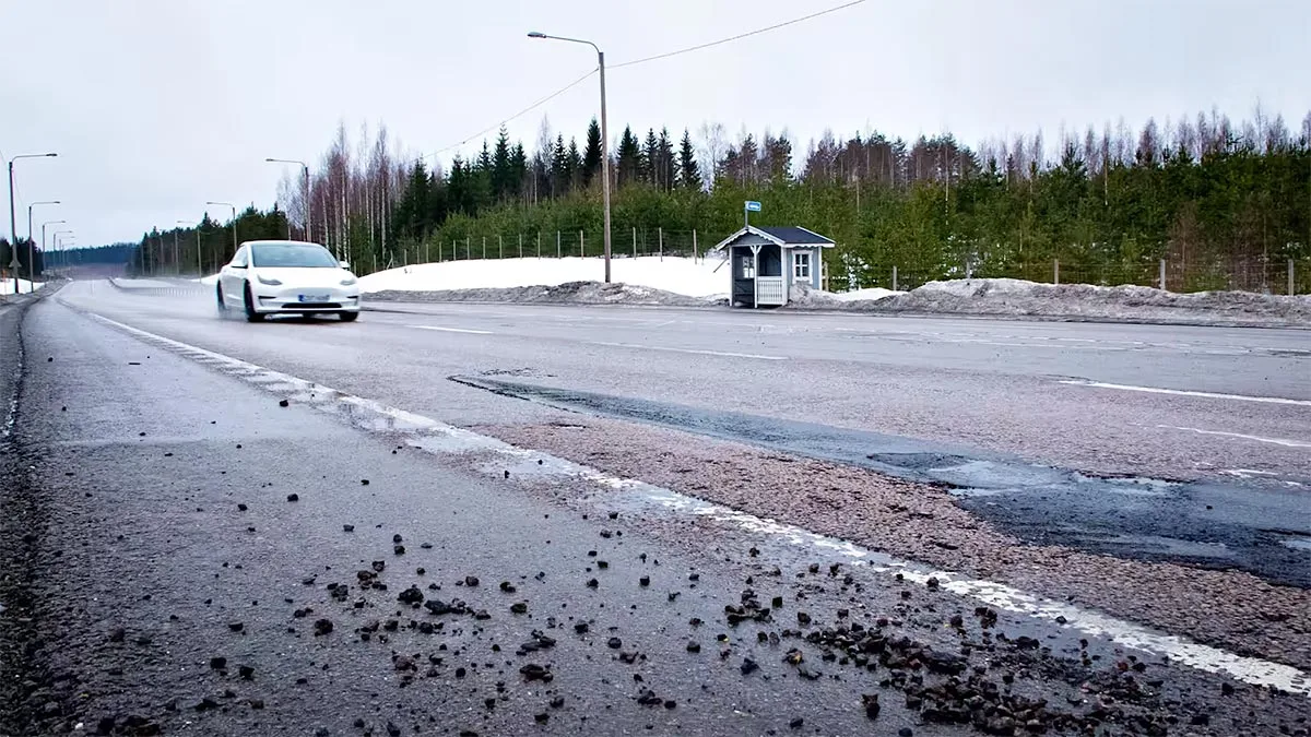 O mașină albă circulă pe un drum înzăpezit, peisaj de iarnă în Suedia.