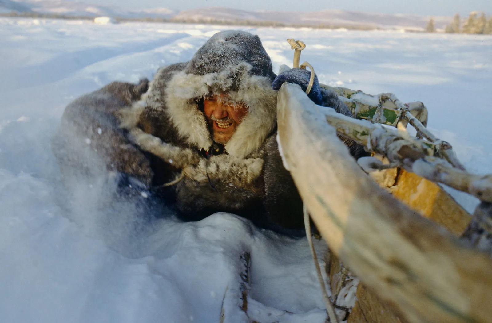 Un bărbat îmbrăcat în blană se află într-un peisaj înghețat din Siberia.