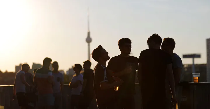 Oameni discutând la apus, cu siluete conturate în lumina soarelui.