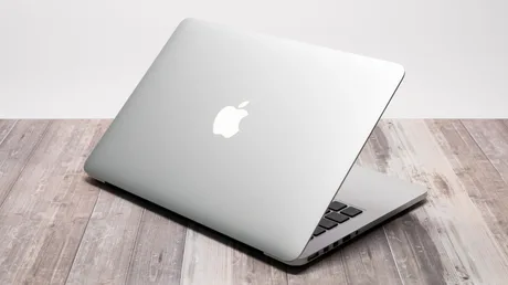 Laptop Apple deschis, cu un design elegant și simplu, fără logo iluminat.