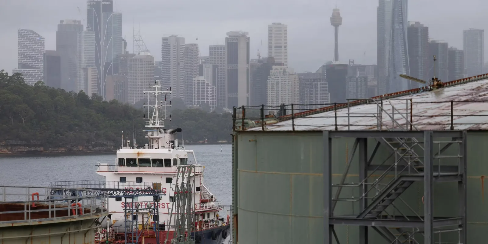 Nave ancorate în port, cu skyline-ul orașului în fundal.