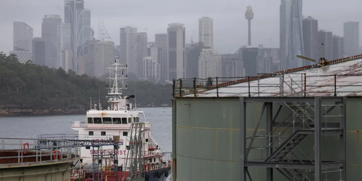 Nave ancorate în port, cu skyline-ul orașului în fundal.