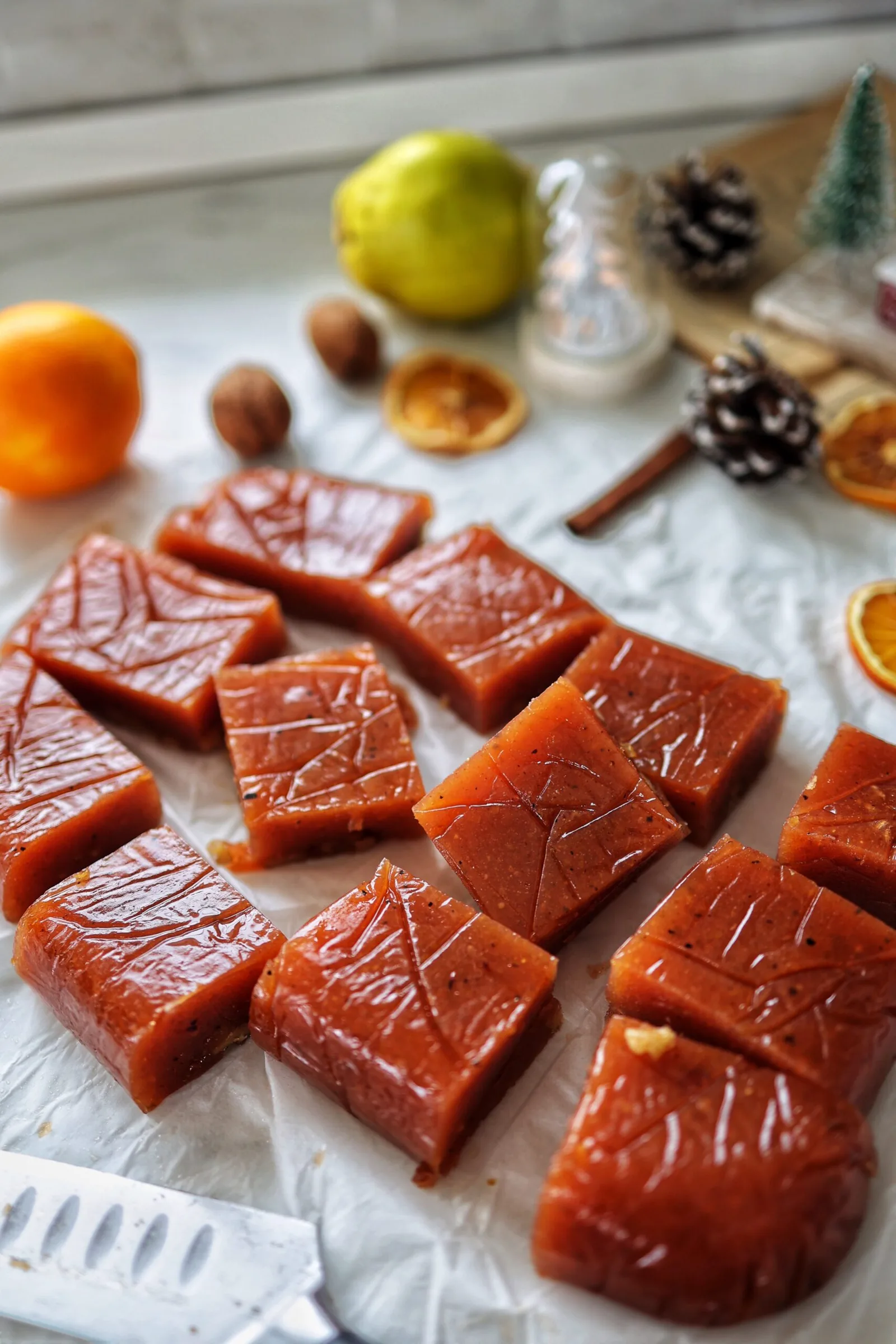 Bucăți de marmeladă de citrice pe o masă decorată cu fructe uscate.