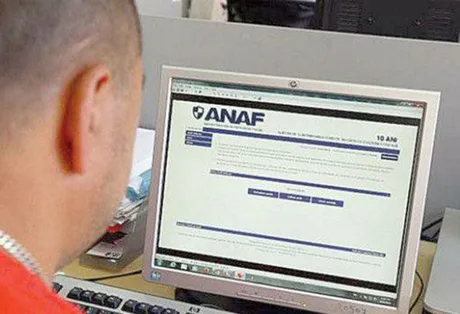 Utilizator pe un computer accesând site-ul ANAF pentru servicii online.