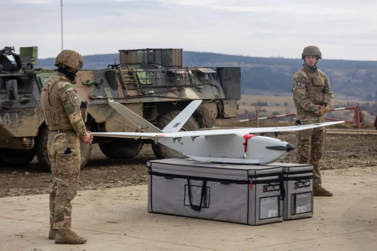 Soldați pregătind o dronă pe un teren de antrenament militar.