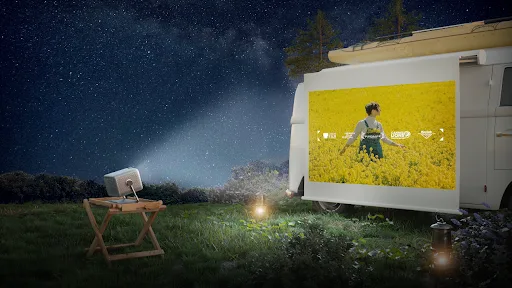 Proiectorul M2SE Pro pe un suport în aer liber, cu imagine pe un ecran mare.