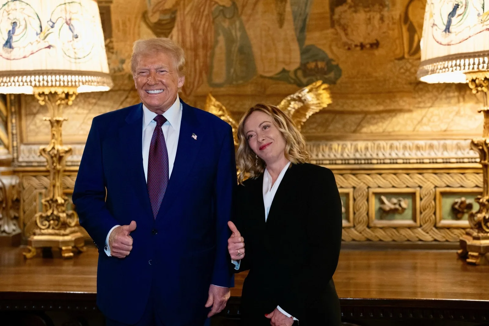 Giorgia Meloni și Donald Trump zâmbind într-un cadru oficial, cu decor elegant în fundal.