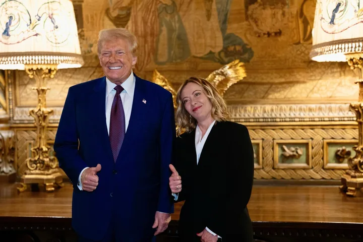 Giorgia Meloni și Donald Trump zâmbind într-un cadru oficial, cu decor elegant în fundal.