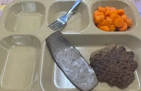 Porție mică de mâncare pe un platou, cu carne și morcovi fierti.