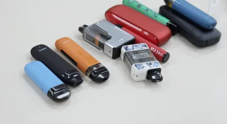 Diverse dispozitive de vaping și țigări electronice pe o masă.