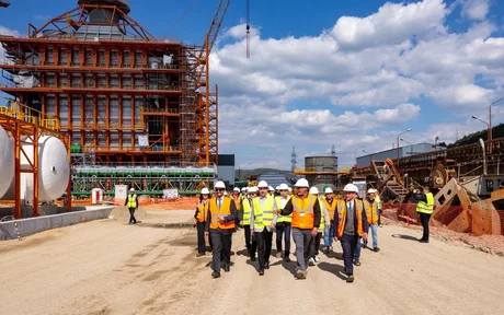 Miniștri PSD inspectând un șantier în construcție, purtând echipamente de protecție.