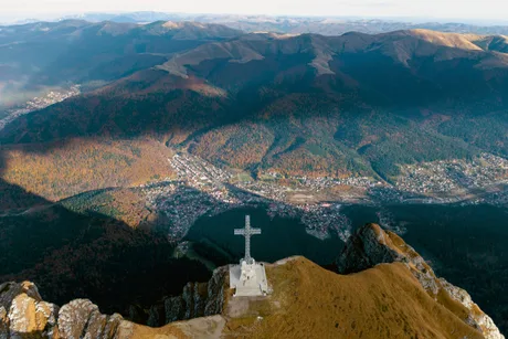 Peisaj montan spectaculos cu crucea de pe vârful muntelui.