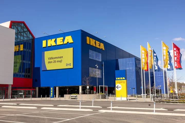 Clădire IKEA cu steaguri și un cer senin în fundal.